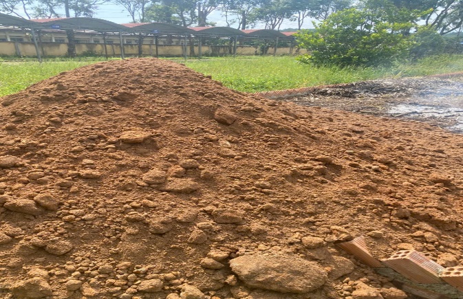 'A pile of dirt next to a fence
Description automatically generated'
